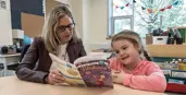 Young student reading with teacher