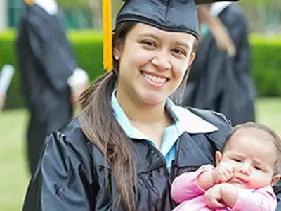 Graduating student with a child in her arms