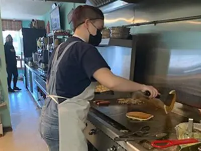 A student cooking on a flat top